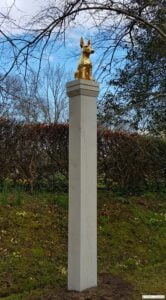Gold dog on tall pillar sculpture
